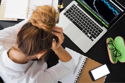 Woman holding head with graph on laptop - Educators Financial Group